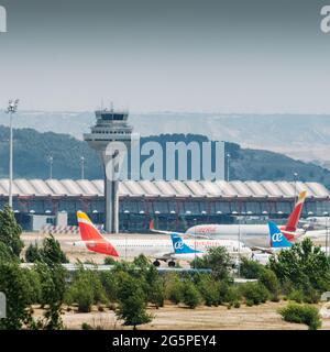 MADRID, SPAGNA - 26 giu 2021: Madrid Bajaras, 26 giugno 2021: Vista ingrandita degli aeroplani su asfalto e il tetto iconico dell'aeroporto di Bajaras a Madrid, Spagna Foto Stock