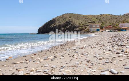 fine della spiaggia dove c'è una grande roccia e ai suoi piedi, le case dei marinai con le loro barche da pesca e l'attrezzatura. Foto Stock