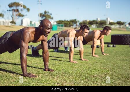 Gruppo vario di uomini muscolari che fanno spingere su esercitarsi all'aperto Foto Stock