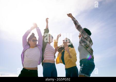 Felice gruppo di diverse amiche che si divertono, con le mani in aria Foto Stock