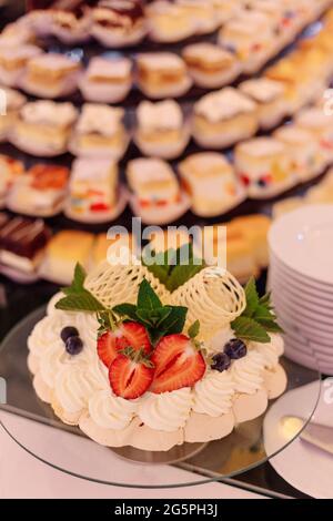 Torta di compleanno decorata con fragole, menta e cioccolato in primo piano della tavola dolce. Eventi di nozze. Pasti in hotel. Eventi festosi. Gusto Foto Stock