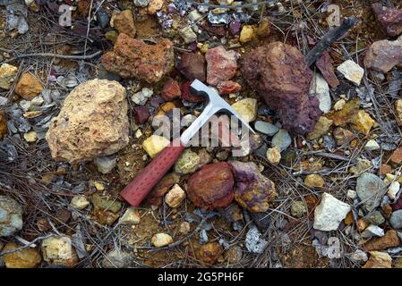 La roccia geologa d'acciaio si accaparrano su rocce colorate rosse e gialle in un'area mineraria ricca di minerali di rame e depositi di solfuro Foto Stock