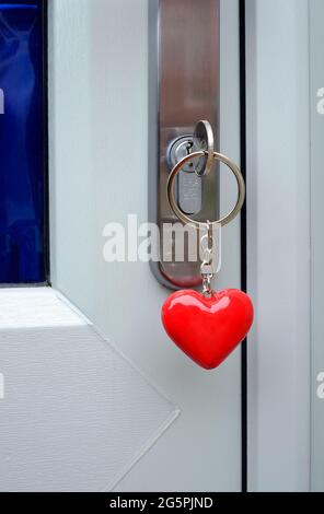 inserire la chiave sul portachiavi rosso a forma di cuore nella serratura della porta Foto Stock