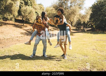 Felice multirazziale giovani piggybacking nella natura Foto Stock