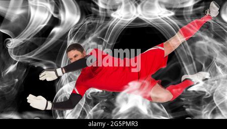 Composizione del portiere maschio che cattura la palla su sfondo nero Foto Stock