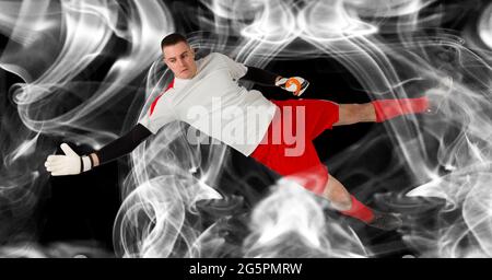 Composizione del portiere maschio che cattura la palla su sfondo nero Foto Stock