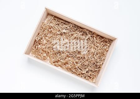 Scatola di legno regalo aperta con riempitivo di carta trinciata su sfondo bianco per il posizionamento del prodotto. Vista dall'alto, mockup Foto Stock