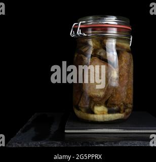 Costolette di maiale, lombo e salsiccia di maiale in vaso, sfondo nero, cucina tipica spagnola Foto Stock