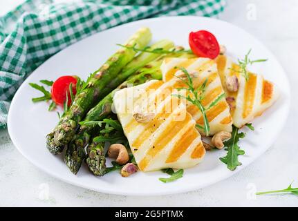 Insalata di formaggio halloumi alla griglia con pomodori e asparagi sul piatto su sfondo chiaro. Cibo vegetariano sano. Foto Stock