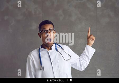 Scioccato africano americano maschio medico che punta più fine su ritratto studio headshot Foto Stock