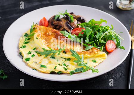 Omelette con formaggio, erbe verdi e funghi fritti sul piatto. Frittata - frittata italiana Foto Stock