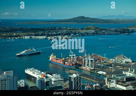 Una vista sul porto di Auckland con una piccola nave da crociera che naviga via, dalla Sky Tower con ormeggi per navi in primo piano. Auckland, Nuova Zelanda Foto Stock