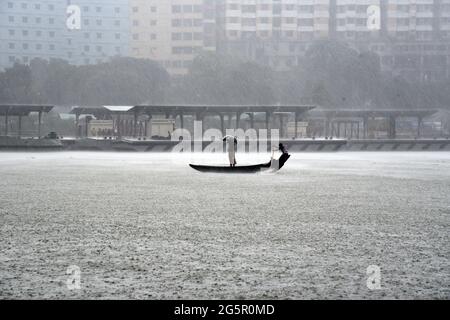 I pendolari del Bangladesh utilizzano le barche per attraversare il fiume Buriganga durante la pioggia a Dhaka, Bangladesh, il 29 giugno 2021. Foto Stock