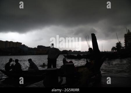 I pendolari del Bangladesh utilizzano le barche per attraversare il fiume Buriganga durante la pioggia a Dhaka, Bangladesh, il 29 giugno 2021. Foto Stock