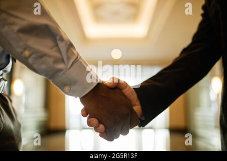 Primo piano di due uomini d'affari che scuotono le mani nella sala dell'edificio dell'ufficio, spazio per le copie Foto Stock