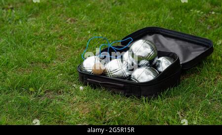 Set di bocce con sei palline di metallo in una custodia nera su erba verde. Gioca nel tuo giardino durante la quarantena. Foto Stock