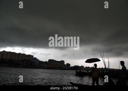 I pendolari del Bangladesh utilizzano le barche per attraversare il fiume Buriganga durante la pioggia a Dhaka, Bangladesh, il 29 giugno 2021. Foto Stock