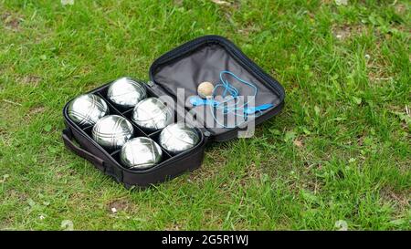 Set di bocce con sei palline di metallo in una custodia nera su erba verde. Gioca nel tuo giardino durante la quarantena. Foto Stock