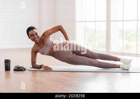 Giovane donna nera che fa la tavola laterale sul tappetino Foto Stock