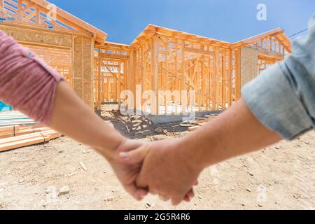 Coppia che tiene le mani guardando la loro New House Framing sotto costruzione. Foto Stock