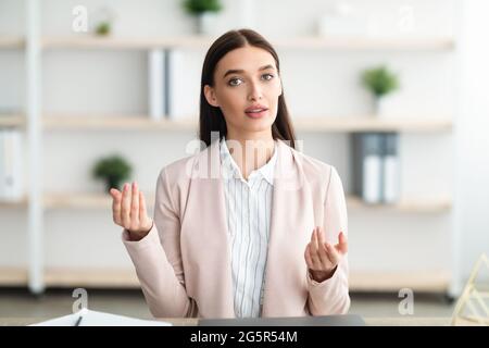 Giovane Businesswoman che parla con Camera Consulting seduto in ufficio moderno Foto Stock