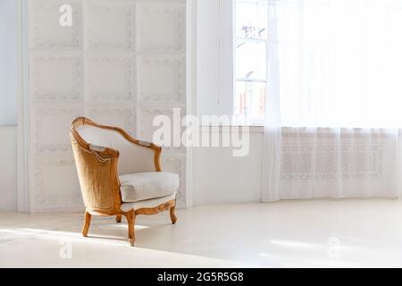 Elegante loft interno camera da letto. Spazioso appartamento di design con pareti luminose, ampie finestre e poltrona. Decorazioni pulite e moderne con arredi eleganti Foto Stock