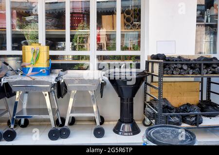 Le nuovissime griglie per barbecue, i carbonai e uno spruzzatore per zaino disinfettante in vendita sono esposti all'esterno di un negozio rurale. Foto Stock