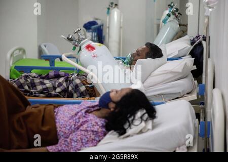 Giacarta, Indonesia. 28 Giugno 2021. Un paziente con difficoltà respiratorie COVID-19 utilizza un tubo per ossigeno all'interno del complesso ospedaliero di emergenza Wisma Atlet Covid-19. L'Indonesia ha registrato un aumento significativo dei casi di COVID-19, registrando in media più di 21,000 casi al giorno che hanno messo sotto pressione gli ospedali, anche a Giacarta e nei suoi dintorni, dove la maggior parte dei letti ospedalieri sono pieni. (Foto di Ria Krisadhi/SOPA Images/Sipa USA) Credit: Sipa USA/Alamy Live News Foto Stock