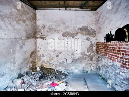 Interno di una camera abbandonata rovina con pareti incrinate e rifiuti sul terreno. Foto Stock