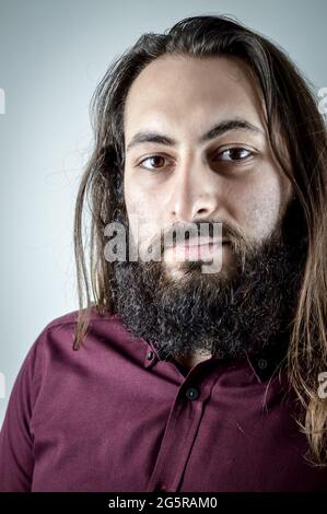ritratto di un giovane uomo d'affari medio orientale con barba e capelli lunghi Foto Stock