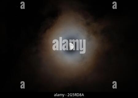 Luna Gibbosa cerosa circondata da nuvole nel cielo notturno Foto Stock