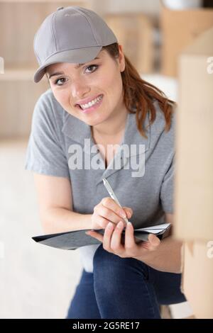 donna felice con appunti al magazzino della società logistica Foto Stock