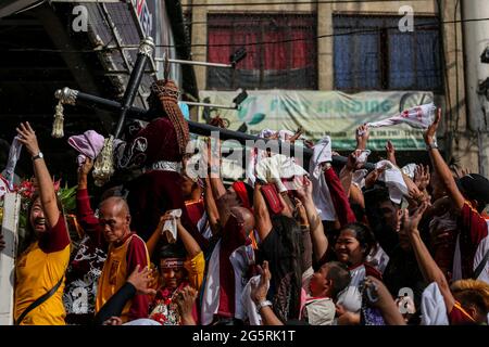 I devoti cattolici filippini alzano le mani e gli asciugamani mentre i sacerdoti spruzzano acqua Santa sulle repliche del Nazareno nero prima della festa del Nazareno nero a Manila, Filippine. Foto Stock