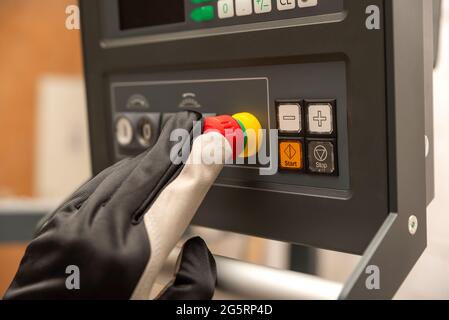 Pulsante di arresto di emergenza in produzione. L'operatore CNC preme il pulsante di emergenza sul pannello di controllo della macchina CNC. Posiziona per il testo Foto Stock