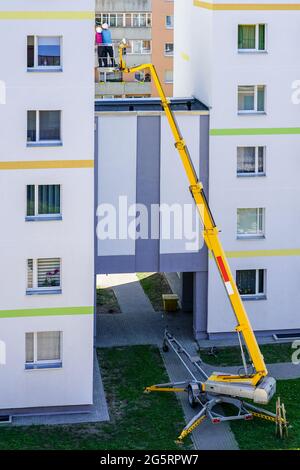 lo specialista ispeziona la facciata della casa con l'aiuto di una moderna piattaforma di sollevamento idraulico semovente mobile Foto Stock