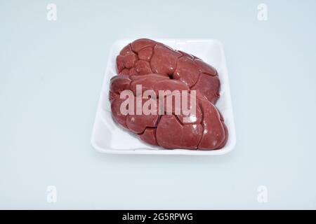 rene di agnello fresco isolato in piastra su fondo bianco, chiocciolo di carne cruda, pezzo di montone Foto Stock