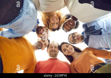 Ritratto a basso angolo di diversi team di persone felici che si accoccolano in una riunione aziendale Foto Stock