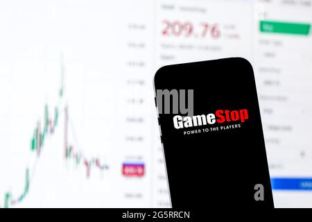 In questa illustrazione fotografica viene visualizzato un logo GameStop su uno smartphone con le informazioni del mercato azionario di GameStop sullo sfondo. Foto Stock