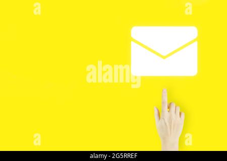 Contattaci idea. Dito della mano della giovane donna che punta con ologramma e-mail segno su sfondo giallo. Concetto di marketing per e-mail e sms Foto Stock