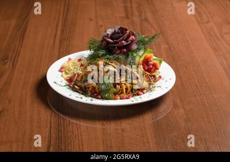 Cucina Asiatica uighur food Kovurma lagman, tagliatelle fritte con carne e pomodoro in un piatto bianco sul tavolo Foto Stock