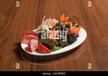 Cucina Asiatica Usbeco cibo Dolma, involtini di cavolo ripieni di riso e manzo macinato avvolto in foglie d'uva in un piatto bianco sul tavolo Foto Stock