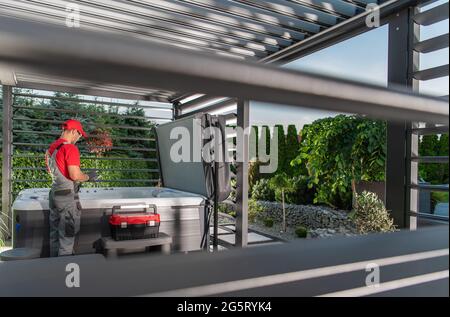 Tecnico professionista della vasca idromassaggio all'interno dei gazebo della vasca idromassaggio che eseguono la manutenzione programmata del sistema di purificazione dell'acqua. Foto Stock