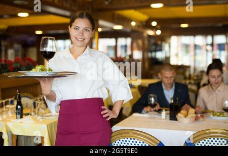 Cameriere in piedi con vassoio di servizio, consigliando i piatti al ristorante Foto Stock