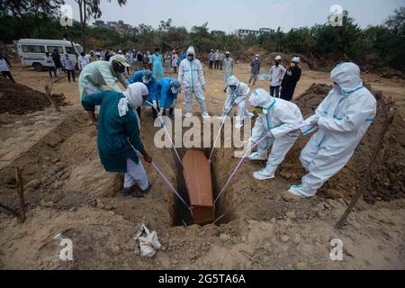 Nuova Delhi, India. 10 Giugno 2020. I medici e i parenti in PPE attrezzatura abbassare una bara in una tomba durante la sepoltura di una vittima che è morto di Covid-19 al cimitero Jadid Qabristan Ahle Islam. Credit: Vijay Pandey/ZUMA Wire/Alamy Live News Foto Stock