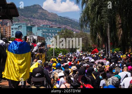 Medellin, Antioquia - Colombia il 28 giugno 2021. Un'ondata di persone è vista come un dimostrante indossa una bandiera nazionale colombiana mentre le proteste anti-governative si scatenano in scontri tra dimostranti e la polizia in rivolta della Colombia (ESMAD), in mezzo a tensioni politiche contro il governo del presidente Ivan Duque, Casi di brutalità e disuguaglianze della polizia mentre la Colombia segna un secondo mese di proteste anti-governative, in ,Medellin, Antioquia - Colombia il 28 giugno 2021. Foto Stock