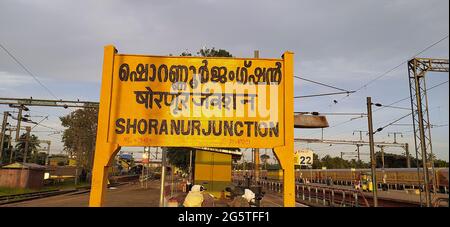 Segno ferroviario 'incrocio di shornur scritto in malayalam (lingua ufficiale del Kerala), hindi e inglese su una piattaforma del raccordo di shoranur Foto Stock