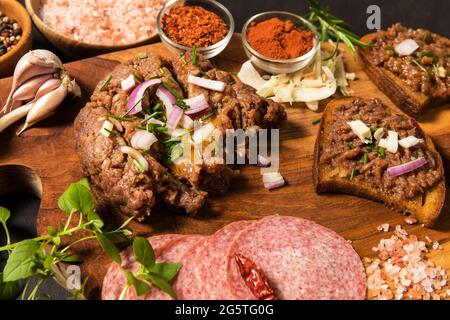 Tradizionale bistecca francese fatta in casa tartare di manzo crudo. Tartaro di bistecca con cipolla tritata ed erbe su tavola di legno. Foto Stock