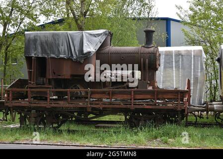 La locomotiva a vapore per il trasporto di merci arrugginite è stata caricata su un vecchio carro in piedi su binari ferroviari ciechi nella zona industriale abbandonata. Foto Stock