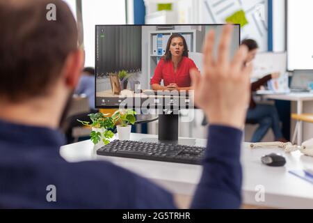 Il manager handicappato parla di videocall con il team leader seduto davanti alla telecamera al computer durante la conferenza virtuale che lavora in un ufficio aziendale strat up. Strategia di pianificazione del team diversificata. Foto Stock