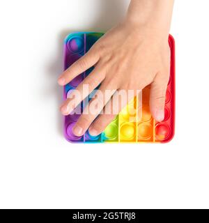 Un bambino spingere sensoriale popit isolato su sfondo bianco. Giocattolo antistress pop it. Fidget sensoriale in silicone arcobaleno. Nuovo e popolare silicio alla moda Foto Stock